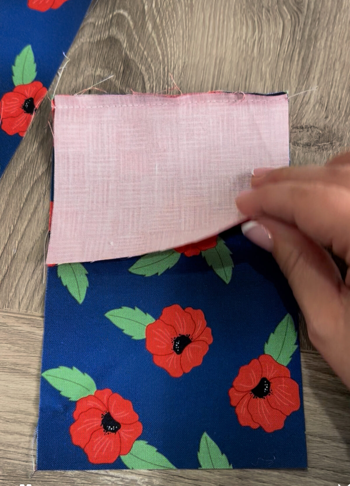 Image contains Amy’s hand placing a piece of fabric right side down on top of a larger piece.
