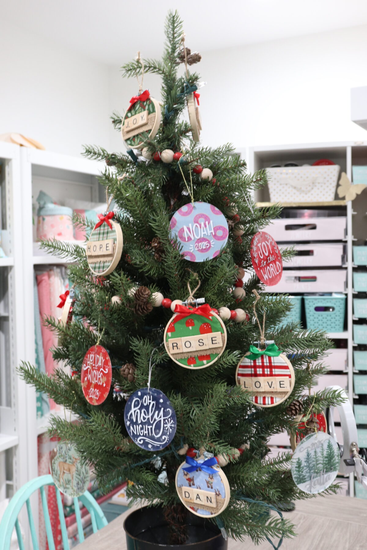 Image contains a small faux Christmas tree decorated with handmade ornaments in a variety of styles and colors.