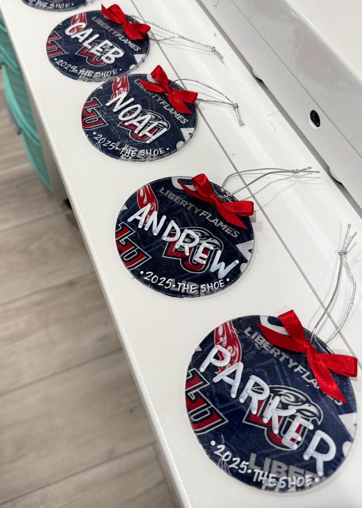 Image contains four round ornaments featuring the Liberty University Logo and names written on top in white print. 
