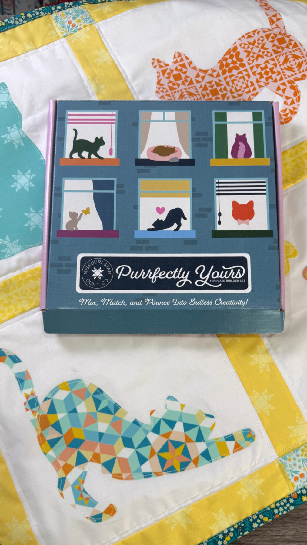 Image contains a box labeled “Purrfectly Yours Template Builder Set” from Missouri Star Quilt Company. It sits on top of a quilted wall hanging.